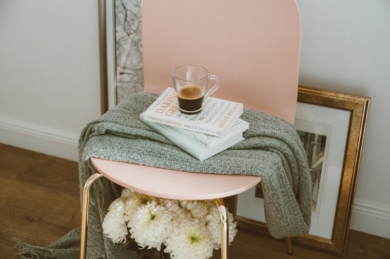 ピンクの椅子の上にあるコーヒーと本