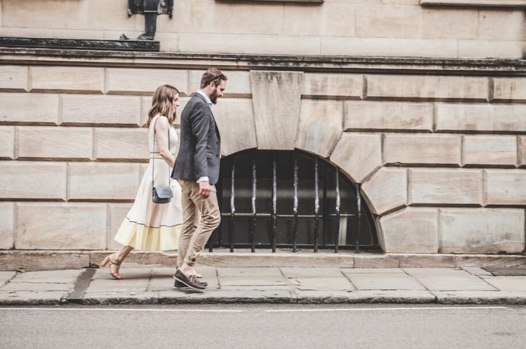 Man and woman wolking beside a road during daytime