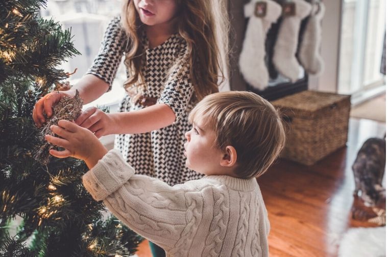 男の子と女の子がクリスマスツリーを飾っている