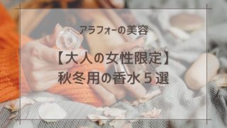 オレンジのセータを着た女性が香水のボトルを持っている